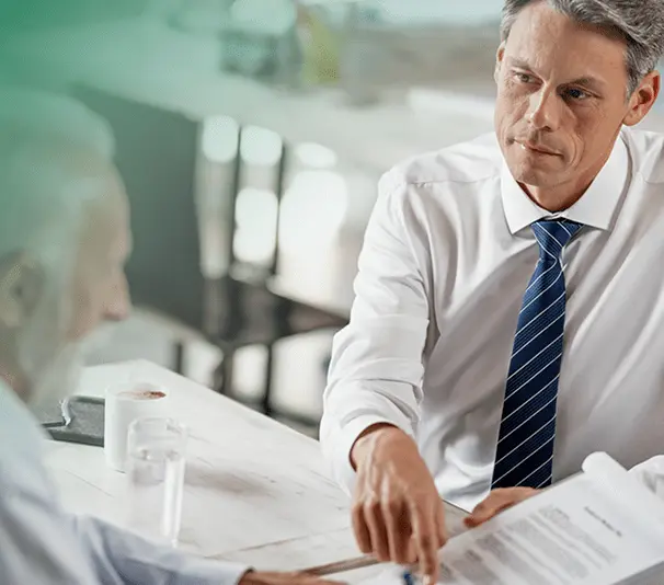 Advisor reviewing documents with elderly client at a table.